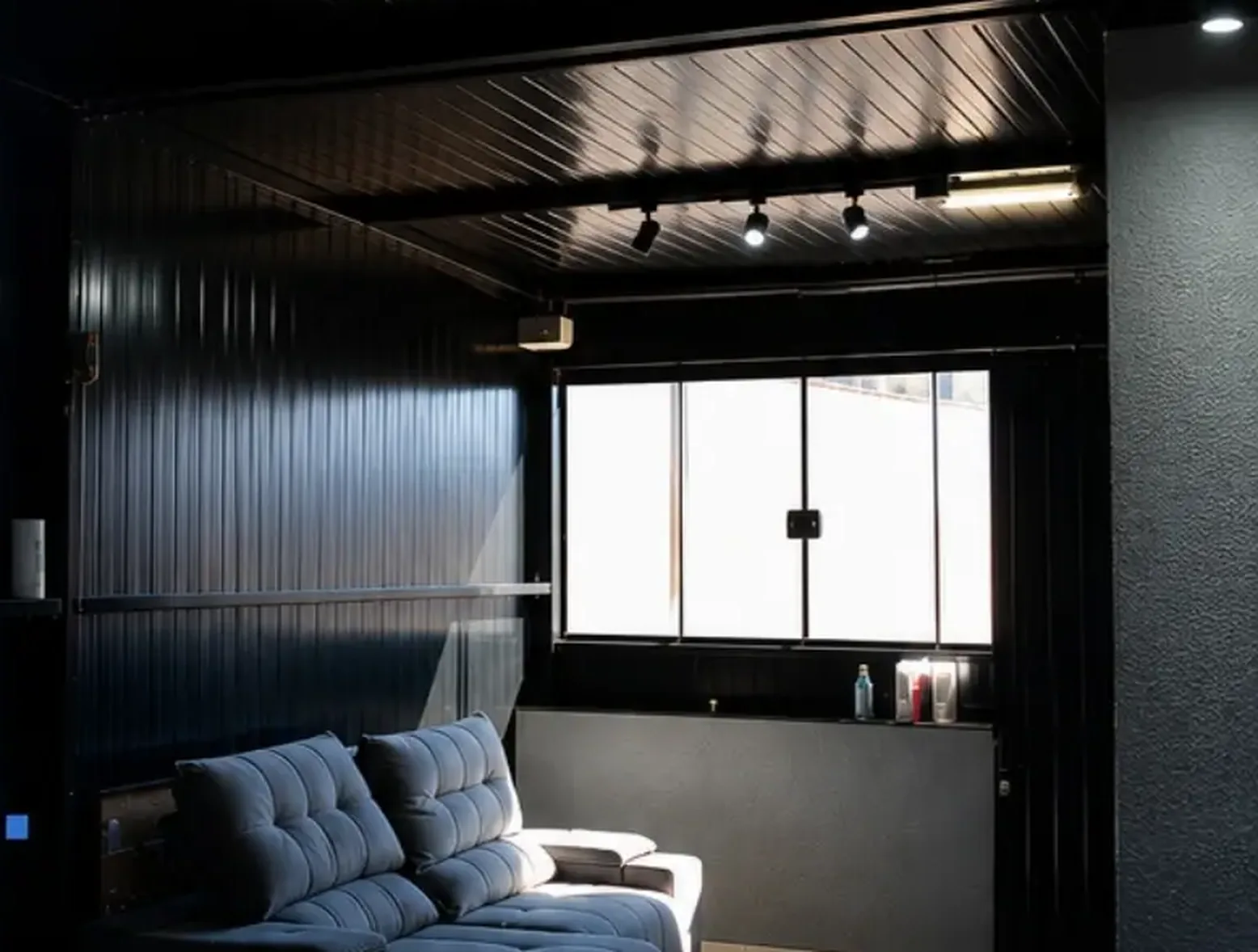 Ambiente interno fechado em estrutura metálica, com forro escuro e iluminação em trilho