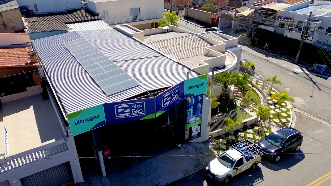 Cobertura metálica vista de cima, com telha ondulada e painéis solares instalados sobre um comércio